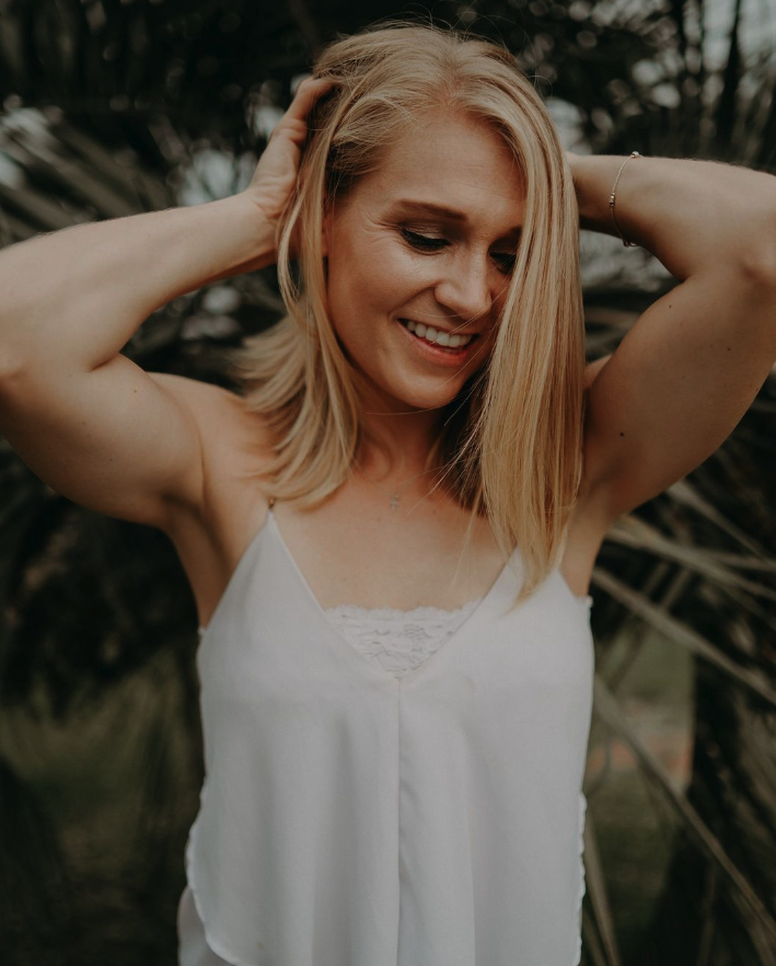 Blonde girl in white shirt holding hair on back of head